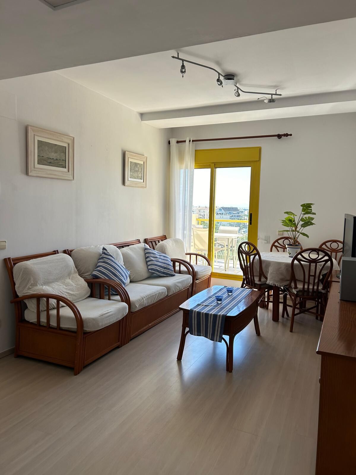 A living room with a sofa, a coffee table, and a dining area with chairs and a table.