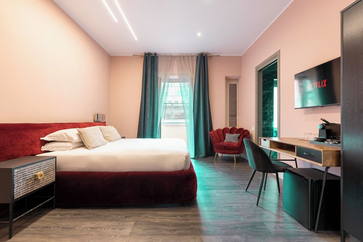 A modern hotel room with a large bed, a desk, a chair, and a TV displaying 'NETFLIX'.