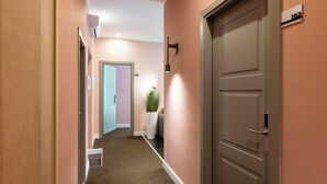 A hallway with a carpeted floor, a door with a number sign, and a potted plant. - My Rooms in Vatican City (Rome)