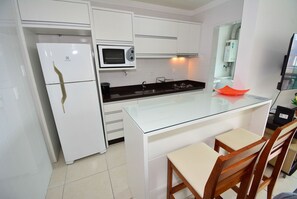 Een moderne keuken met witte kastjes, een glazen kookeiland, een magnetron en een spoelbak.