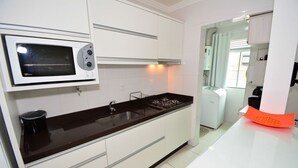 Una cocina moderna con armarios blancos, encimera negra, microondas integrado y cocina a gas.
