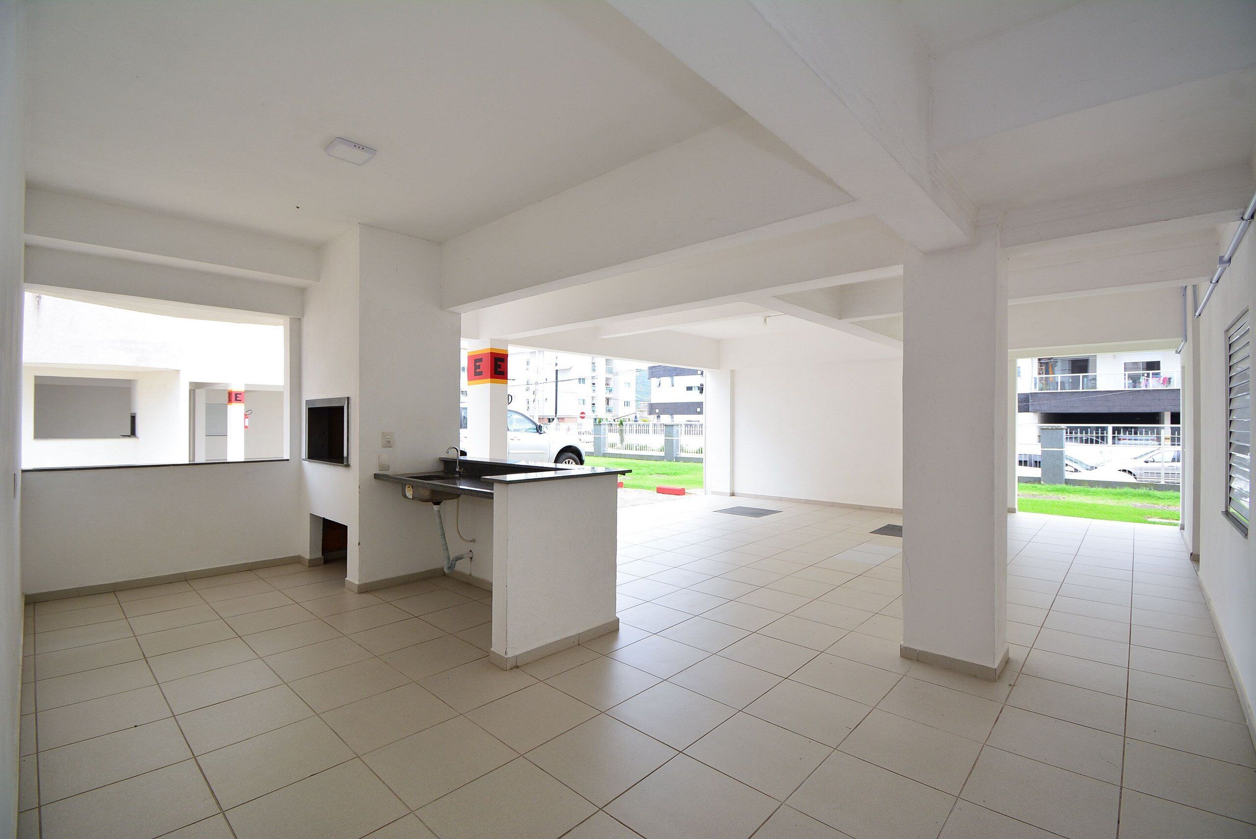 A spacious, well-lit interior with a kitchen area, large windows, and a view of the outside.