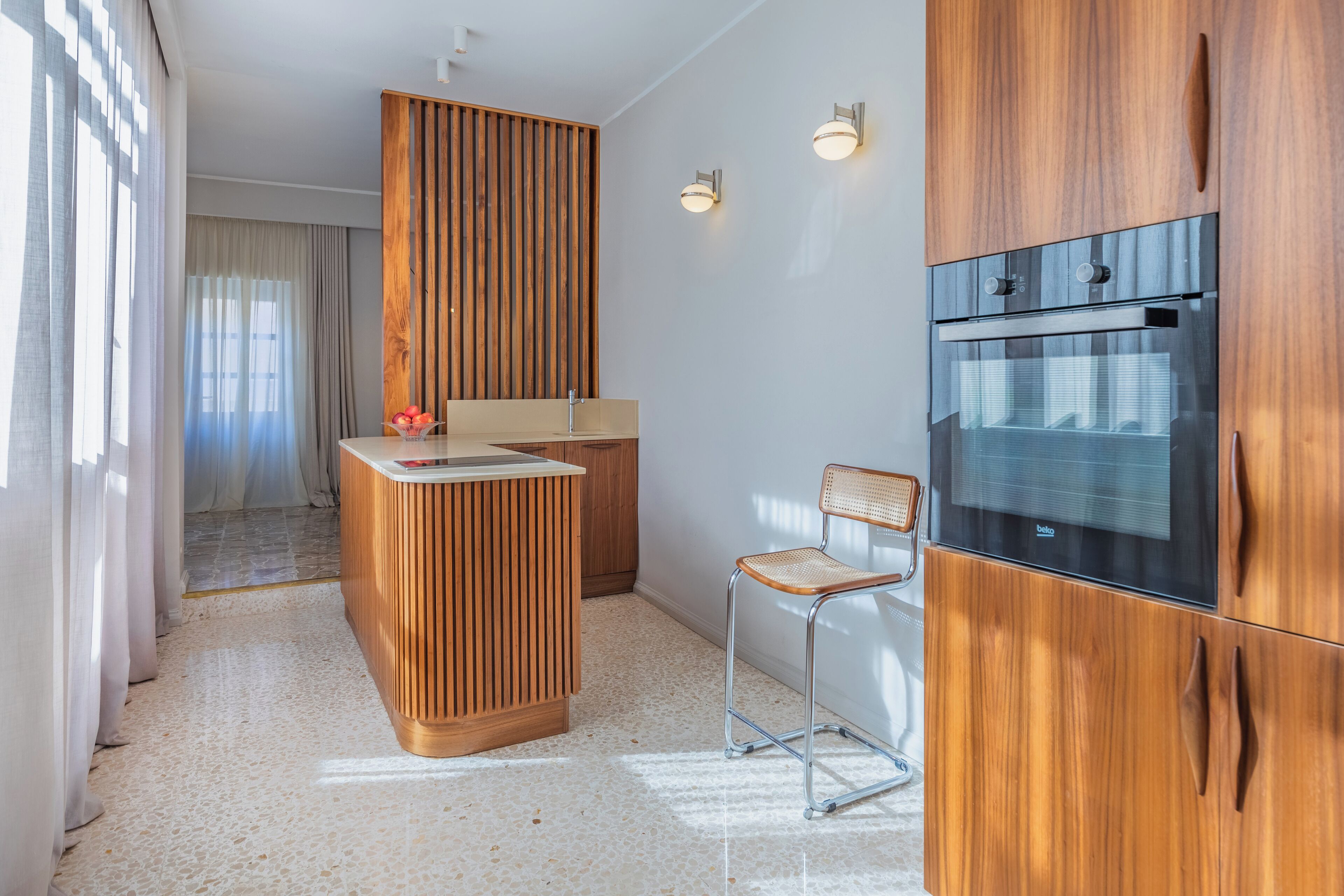 A modern kitchen with wooden cabinetry, a built-in oven, and a small island with a sink.