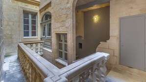 A stone building with a balcony, a door, and a light fixture. - House of W (Valletta)
