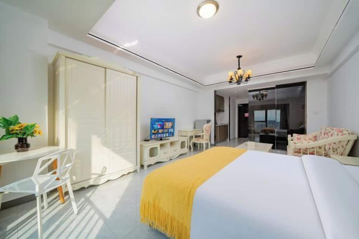 Ein modernes Hotelzimmer mit einem Bett, einem Schreibtisch mit Stuhl, einem Fernseher und einem Kleiderschrank.