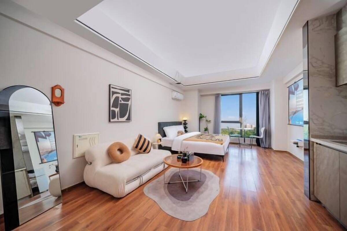 Ein modernes Hotelzimmer mit einem großen Bett, einem Sofa, einem Couchtisch und Blick ins Freie.