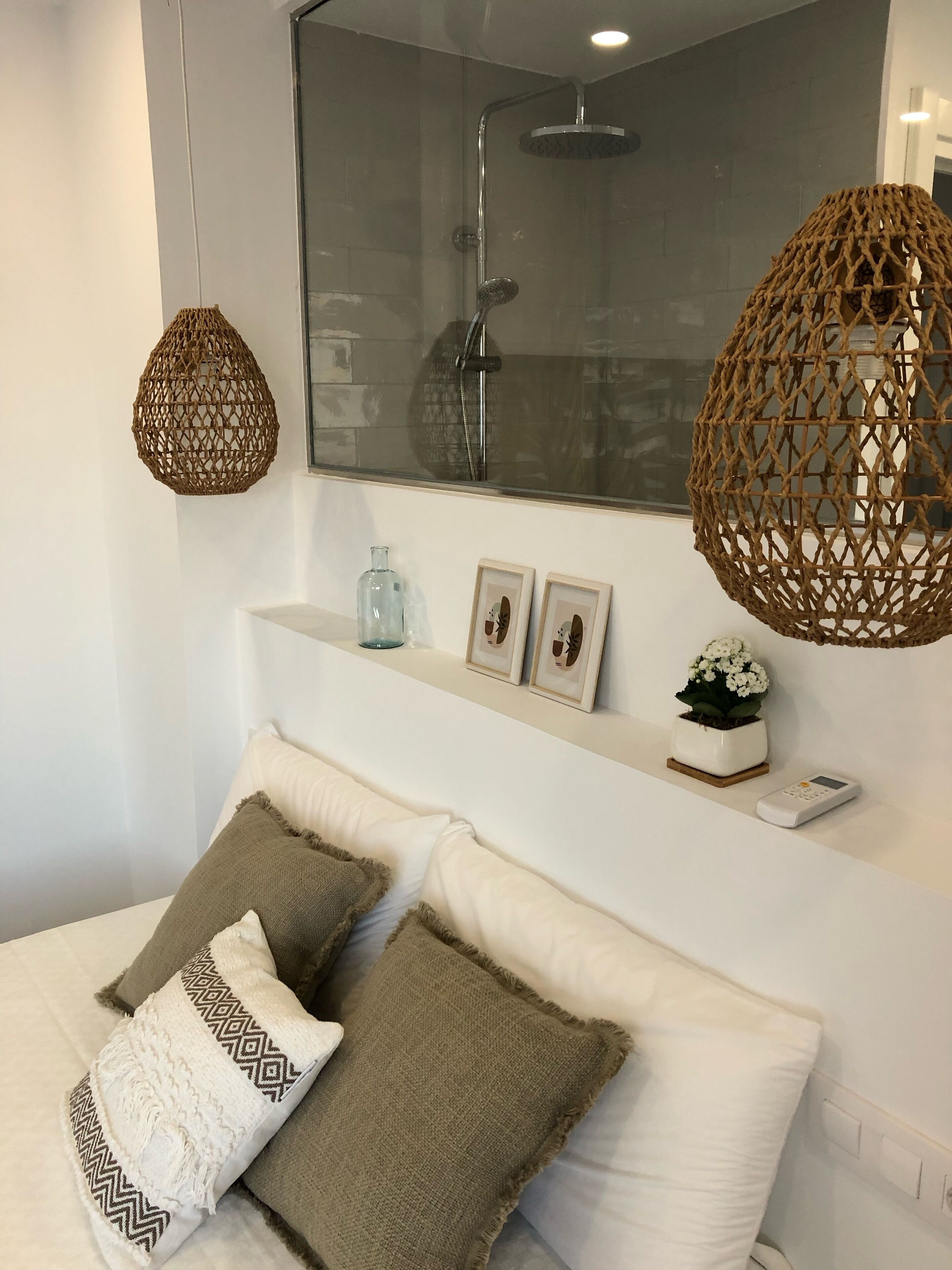 A modern bathroom with a glass shower enclosure, a white vanity, and two hanging woven light fixtures.