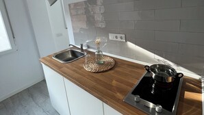 A modern kitchen with a wooden countertop, a built-in stove, a sink, and a pendant light. - Estudios Peñiscola  (Peñíscola)