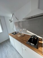 Una cocina moderna con encimera de madera, estufa integrada, pileta y lámpara colgante.
