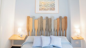 Une chambre à coucher avec un lit, une tête de lit en bois, des tables de chevet, des lampes et un tableau encadré au mur.
