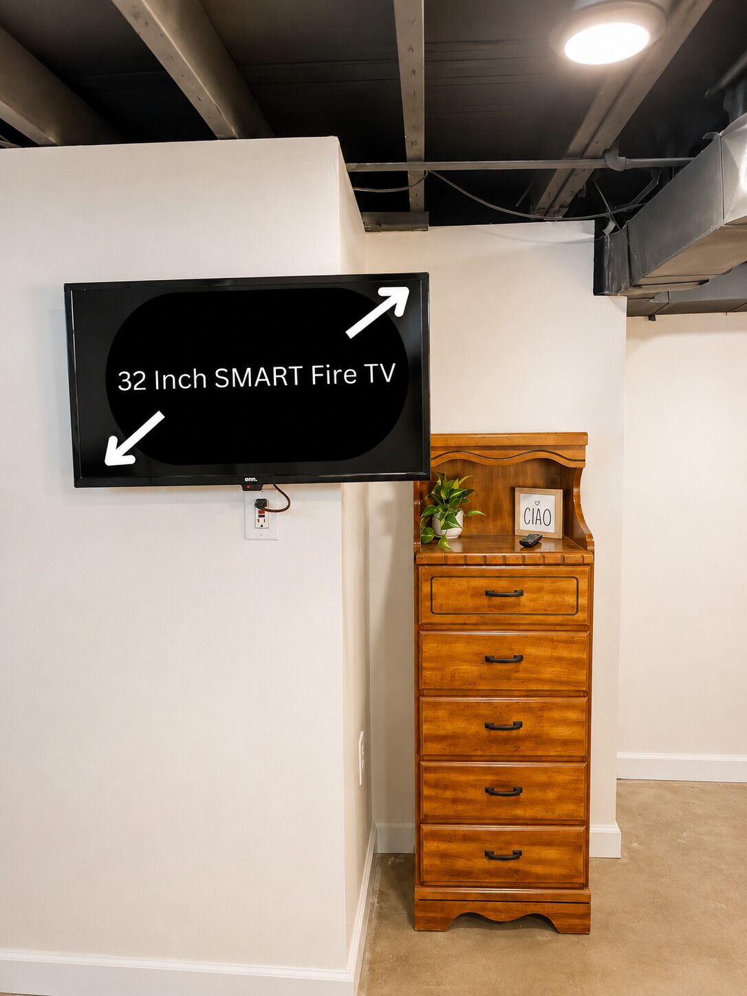 A 32-inch SMART Fire TV mounted on a white wall with a wooden dresser beside it.