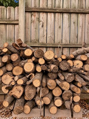 A stack of cut logs against a wooden fence.