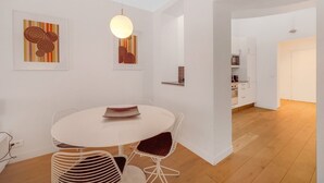 Ein moderner Essbereich mit einem runden Tisch und Stühlen, einer hängenden Leuchte und zwei gerahmten Kunstwerken an der Wand.