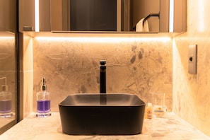 A bathroom with a black sink, a marble countertop, and a mirror above the sink. - Beach Haus by Carpediem (João Pessoa)