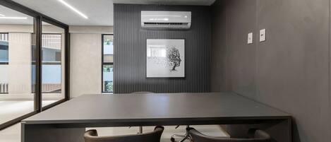 A conference room with a long table, two chairs, an air conditioning unit, and a framed artwork on the wall.
