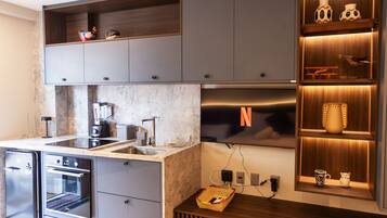 Una cocina moderna con electrodomésticos integrados, encimera de mármol y estanterías de madera con objetos decorativos.