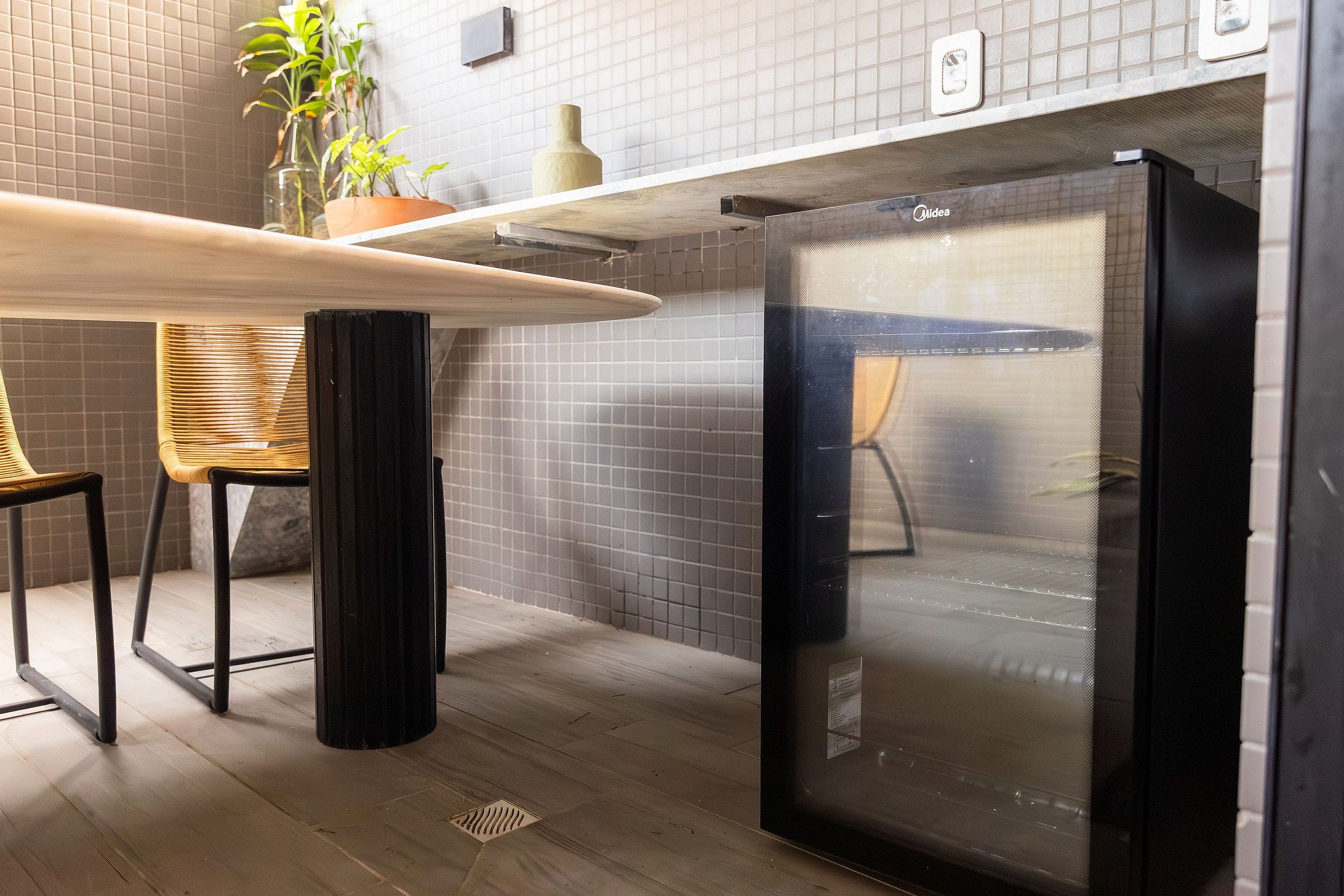 A kitchen with a black refrigerator, a wooden table, and two chairs.