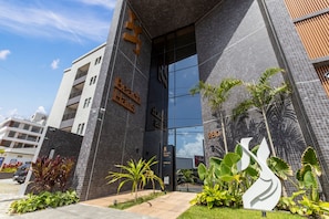 A modern building with a large glass entrance, a sign reading 'Beach House Delivery,' and a number '280' on the side. - Beach Haus by Carpediem (João Pessoa)