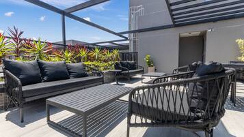 An outdoor patio with seating, tables, and potted plants.