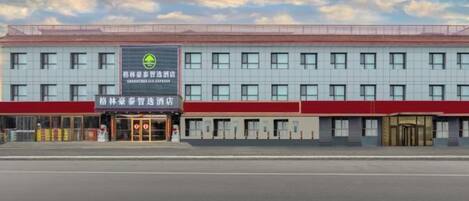 A hotel with a red and white facade, multiple windows, and a prominent entrance.
