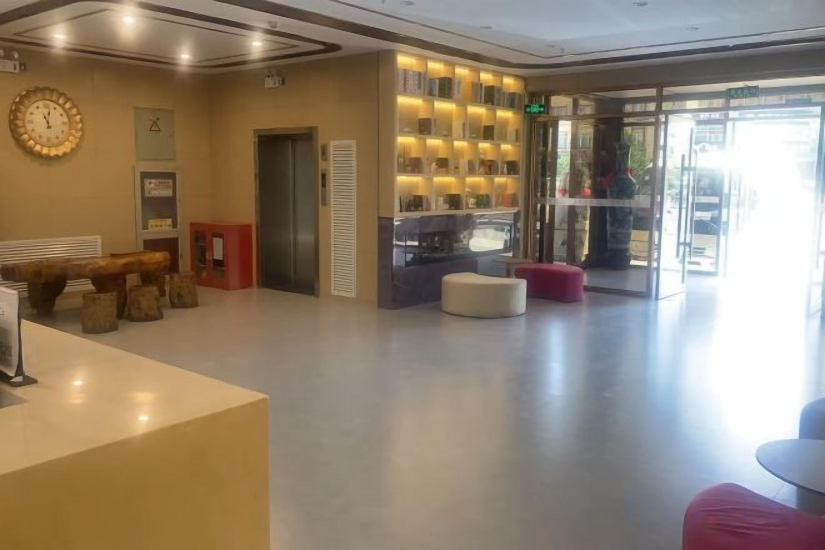 A hotel lobby with a reception desk, seating area, and a glass door entrance.