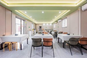 Un comedor con mesas y sillas, una cocina al fondo y vistas a la calle.