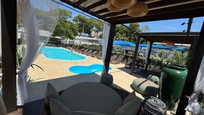Uma área externa coberta com piscina, espreguiçadeiras e uma mesa.