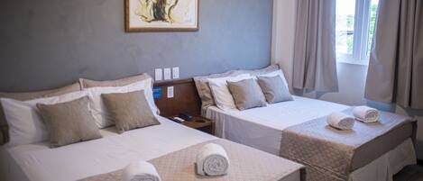 A hotel room with two beds, each with a quilted bedspread and pillows, a nightstand with a phone, and a framed artwork on the wall.