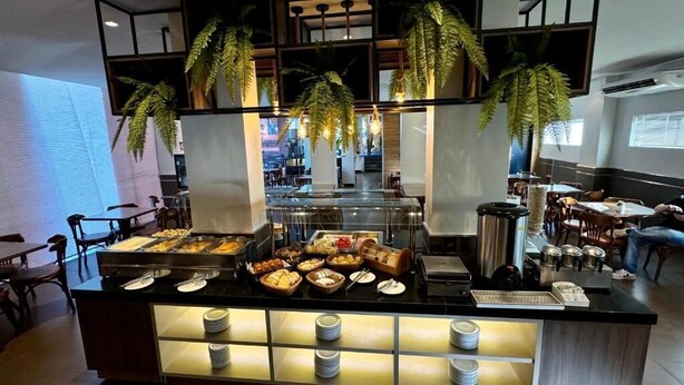 Uma área de buffet com diversos alimentos e um balcão com pratos e talheres.
