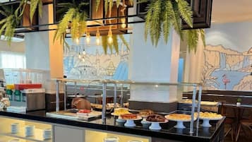 A buffet area with various food items and a mural on the wall.