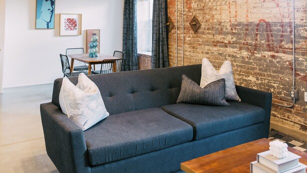 A modern living room with a dark blue sofa, a wooden coffee table, and a patterned rug.