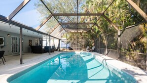 A swimming pool with a glass ceiling, surrounded by lounge chairs and a covered patio area. - Private Pool Home near 5th Ave, Old Naples and Beach (Naples)