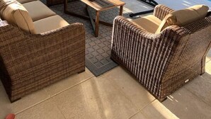 A covered outdoor seating area with wicker furniture and a pool in the background. - Private Pool Home near 5th Ave, Old Naples and Beach (Naples)