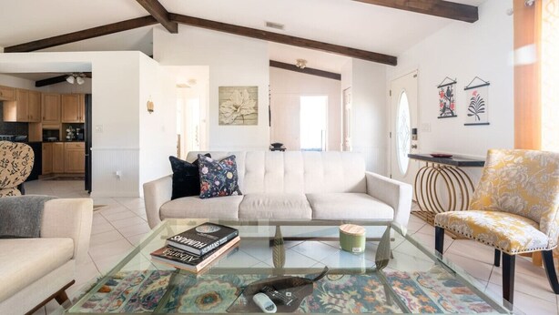 A living room with a sofa, armchairs, a coffee table, and a kitchen in the background. - Private Pool Home near 5th Ave, Old Naples and Beach (Naples)
