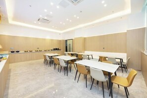 Un espace repas moderne avec plusieurs tables et chaises, un comptoir de cuisine et une grande fenêtre.