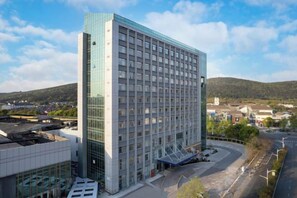 Un hôtel moderne doté d’une façade en verre, d’une entrée couverte et offrant une vue sur les environs.
