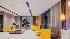 A modern hotel lobby with yellow armchairs, a sofa, and a reception desk. - Motel (Shanghai Lujiazui Yushan Road Yuanshen Sports Center) (Shanghai)