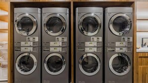 Four stacked front-loading washing machines in a row, each with a control panel and a circular door. - Motel (Shanghai Lujiazui Yushan Road Yuanshen Sports Center) (Shanghai)