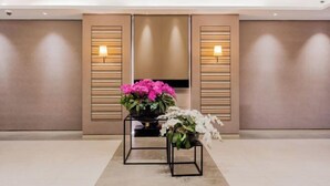 A modern hotel lobby with a minimalist design, featuring a reception desk with a potted plant and a wall-mounted lamp. - Motel (Shanghai Lujiazui Yushan Road Yuanshen Sports Center) (Shanghai)