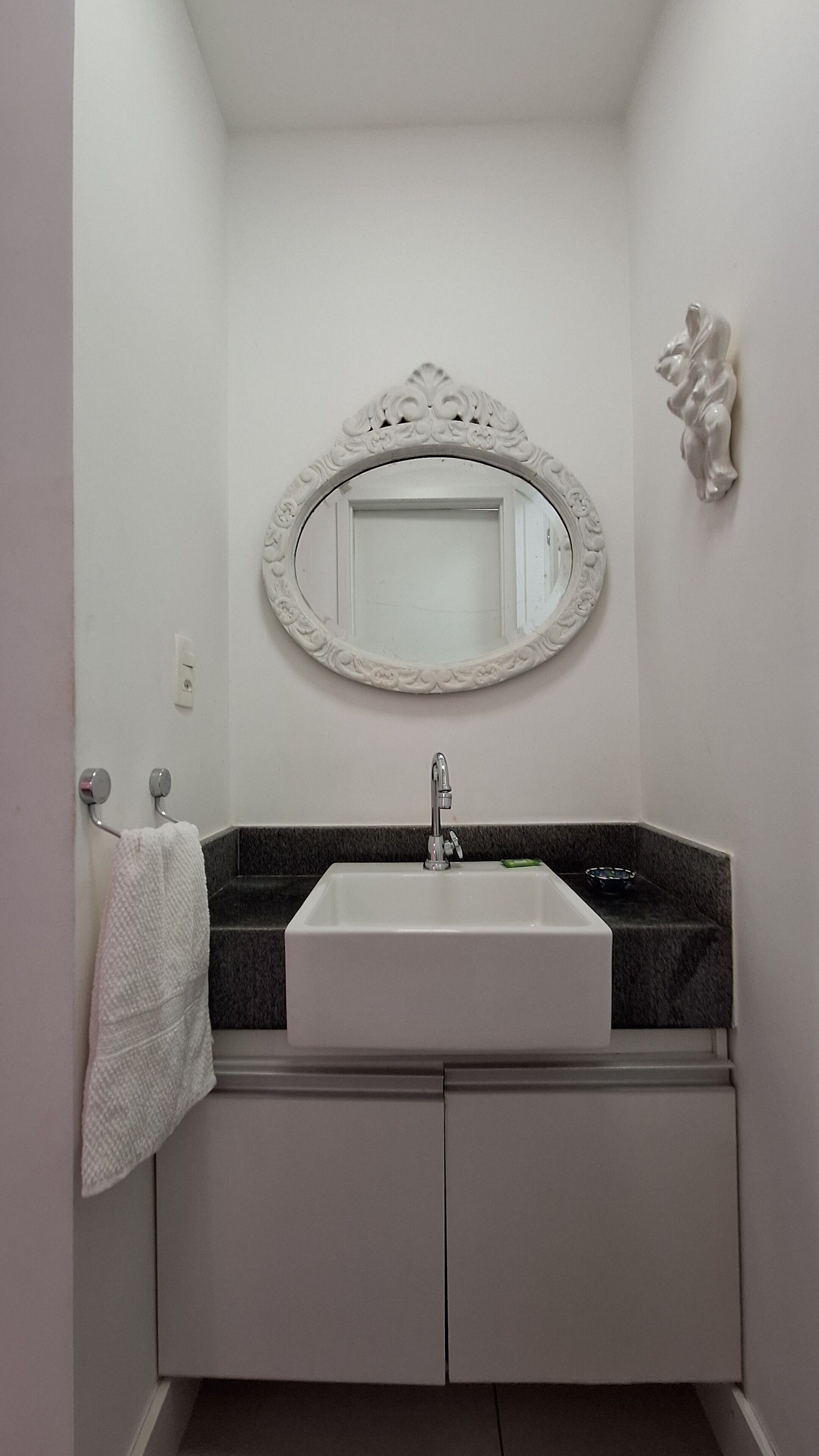 A bathroom with a white sink, a mirror with an ornate frame, and a towel rack.