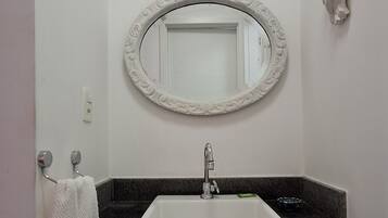 A bathroom with a white sink, a mirror with an ornate frame, and a towel rack.