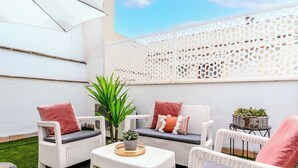 A patio with wicker furniture, cushions, a small table, and a potted plant. - Francos Cathedral Terrace Apartment (Sevilla)