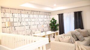 Una sala de estar con una estantería, una mesa de centro, un sofá y una cuna.