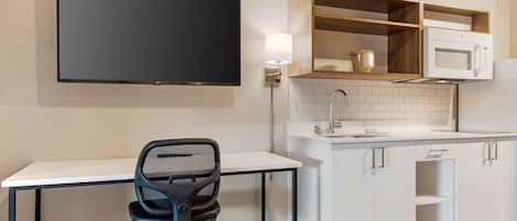 A compact kitchen with a flat-screen TV, a microwave, and a sink.