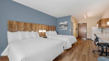 Een hotelkamer met twee bedden, een kitchenette en een badkamer.