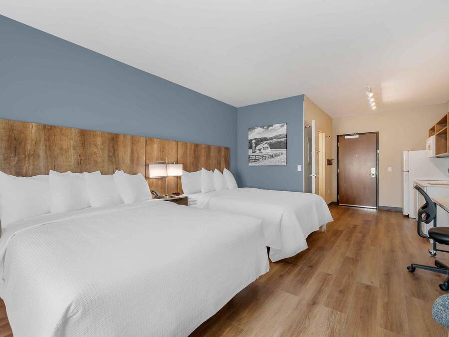 Een hotelkamer met twee bedden, een kitchenette en een badkamer.