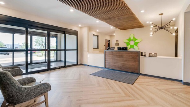 A reception area with a wooden ceiling, a reception desk, a green decorative piece, and a large window with a view of the outside. - Extended Stay America Premier Suites – Phoenix - Chandler – Airport (Chandler)