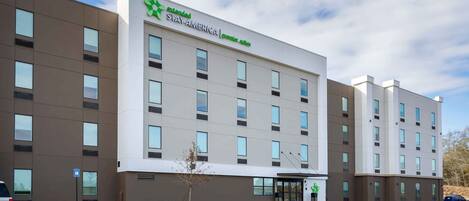 Ett Stay America Premier Suites-hotell med en modern fasad, många fönster och en parkeringsplats.