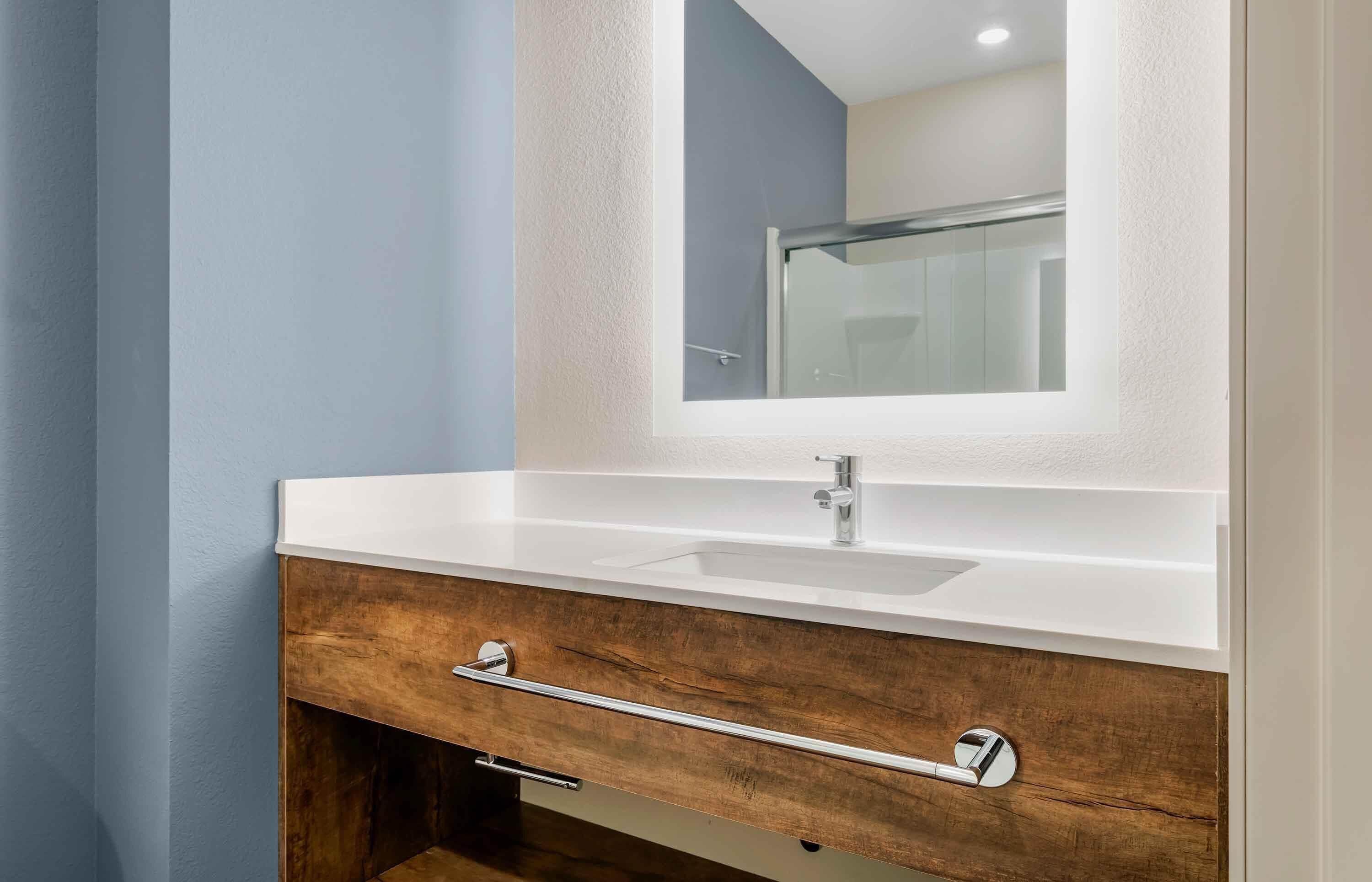 Ein Badezimmer mit Waschbecken, Holzschrank und Spiegel.