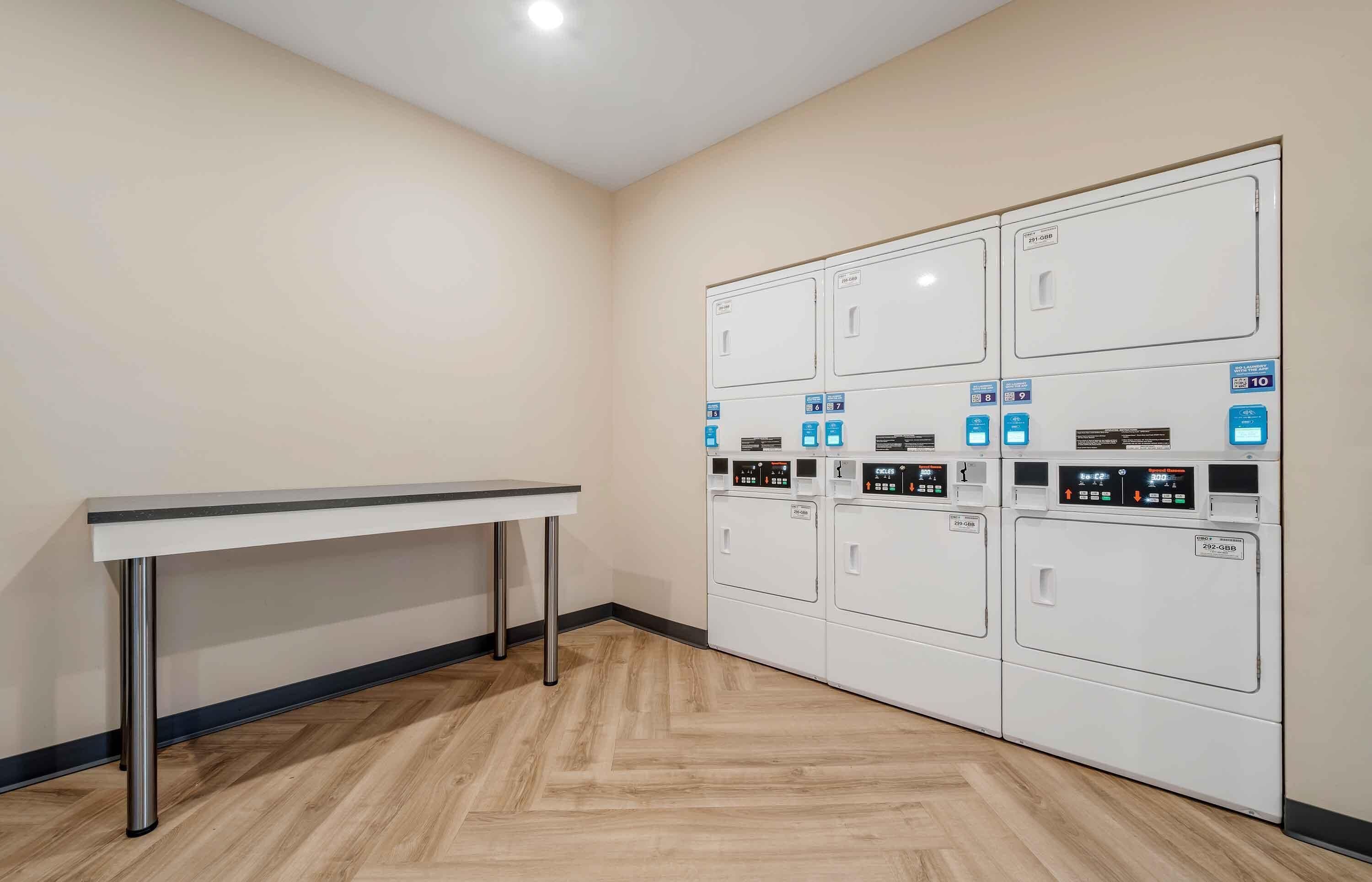 A laundry room with a table and multiple washing machines.